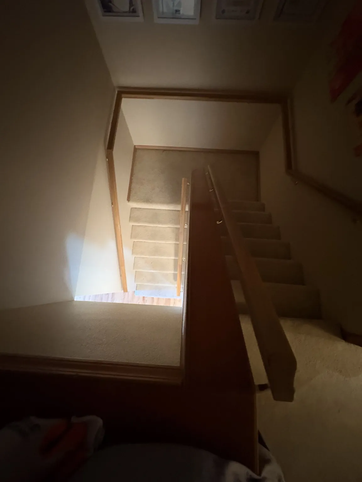 A carpeted indoor staircase with a landing and wooden banister.