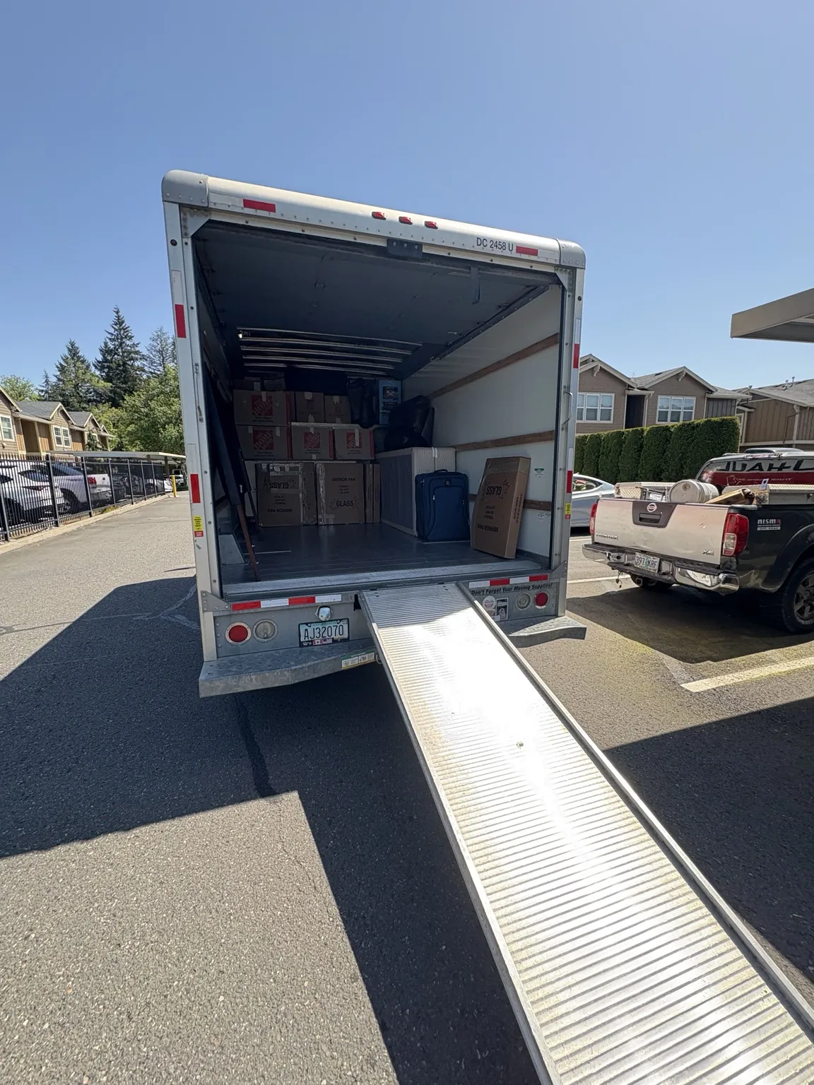An open rental truck with a loading ramp in an apartment parking area.